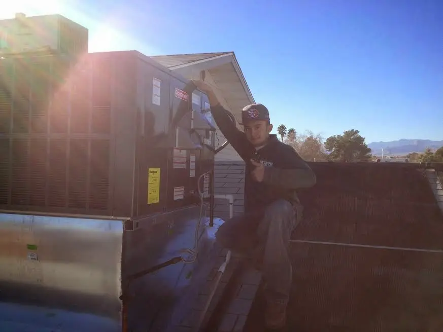 HVAC technician performing Air Duct Cleaning on a rooftop unit in Dacono