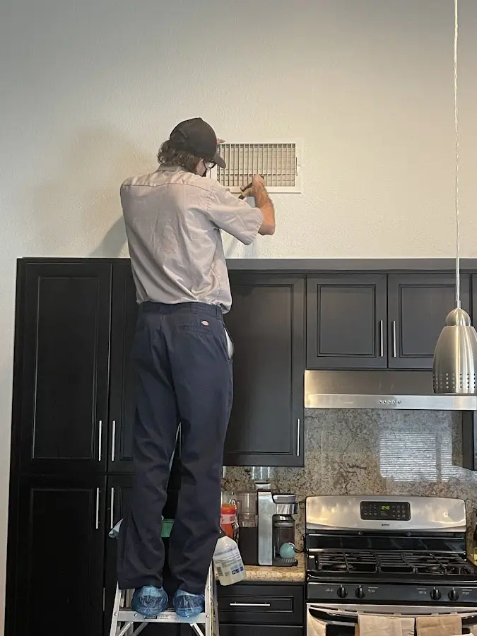 Technician inspecting an air vent during HVAC service in Dacono